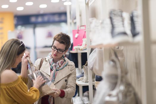 Two Girl-Friends On Shopping Walk On Shopping Centre With Bags And Choosing