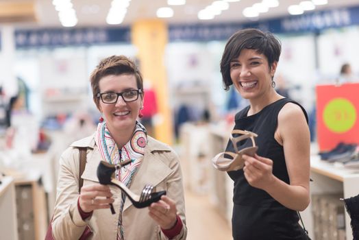 Two Girl-Friends On Shopping Walk On Shopping Centre With Bags And Choosing