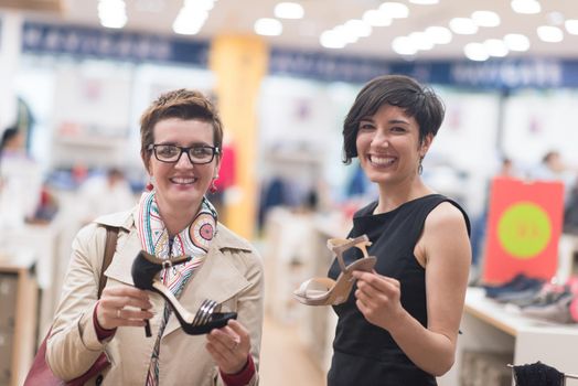 Two Girl-Friends On Shopping Walk On Shopping Centre With Bags And Choosing