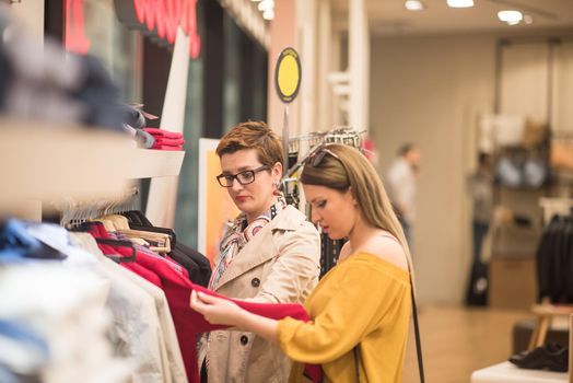 Two Girl-Friends On Shopping Walk On Shopping Centre With Bags And Choosing