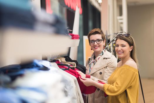 Two Girl-Friends On Shopping Walk On Shopping Centre With Bags And Choosing