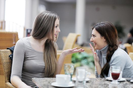 very cute smiling women drinking a coffee sitting inside in cafe restaurant