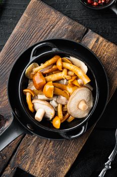 Canned mushrooms in oil set, on black wooden table background, top view flat lay