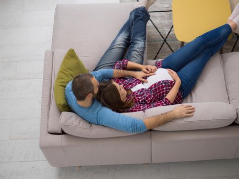 top view of happy pregnant couple relaxing on sofa couch at home