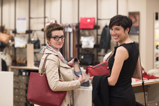 Two Girl-Friends On Shopping Walk On Shopping Centre With Bags And Choosing