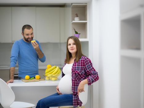 young pregnant couple cooking food fruit lemon juice at kitchen, lifestyle healthy pregnancy happy life concept