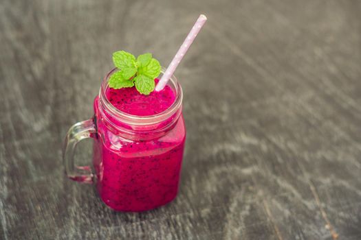 Smoothies of a red organic dragon fruit on an old wooden background.