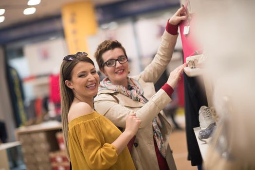 Two Girl-Friends On Shopping Walk On Shopping Centre With Bags And Choosing