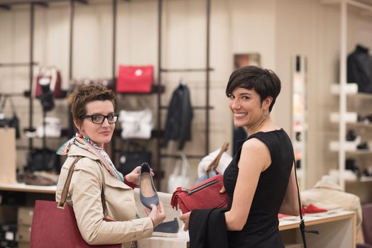 Two Girl-Friends On Shopping Walk On Shopping Centre With Bags And Choosing