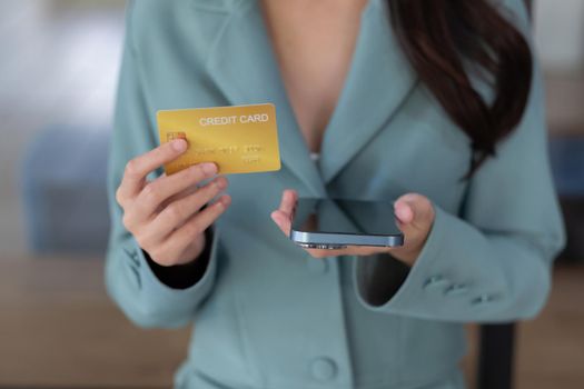 Close up woman in a cafe shopping online with credit card and mobile phone.