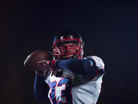 american football player throwing rugby ball against black background