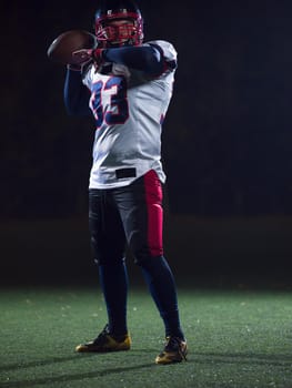 american football player throwing rugby ball against black background