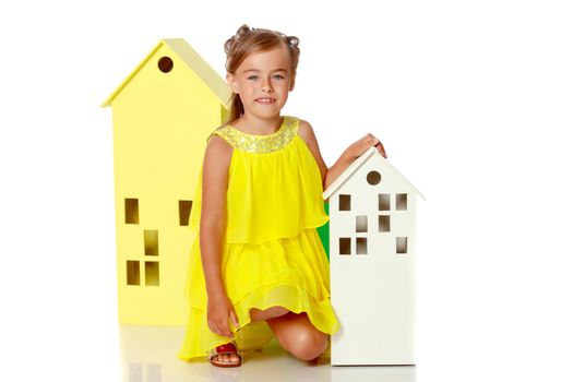 A cute little girl is playing with wooden houses. The concept of family happiness, play, creative development of the child.