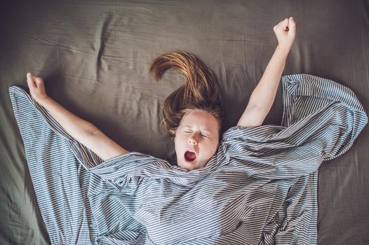 Beautiful young woman lying down in bed and sleeping, top view. Do not get enough sleep concept.