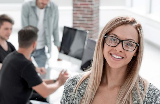 A young girl stands in the office with her arms crossed. Business people showing team work while working in a board room in office interior. Business concept. Team work.