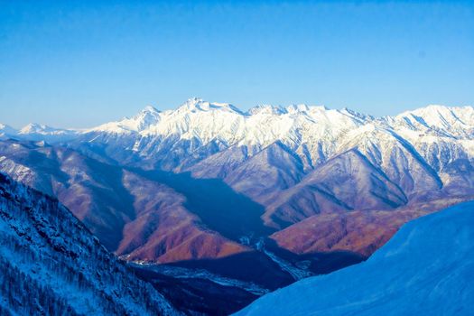 Magnificent view on a sunny frosty day, on the snow-covered mountain peaks lit by the morning sun. The concept of a family vacation, a photo on the advertising booklet. Sochi. Russia.