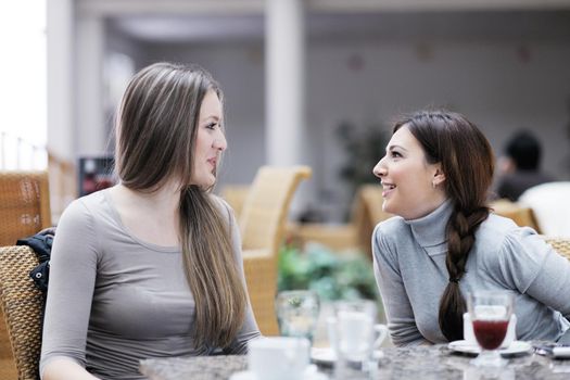 very cute smiling women drinking a coffee sitting inside in cafe restaurant