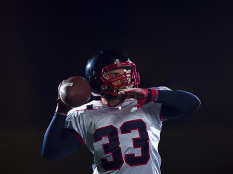 american football player throwing rugby ball against black background