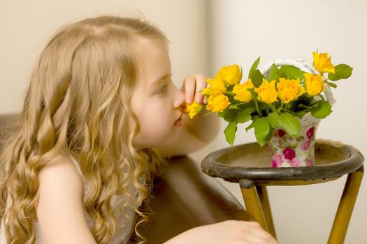 Happy little girl sniffs flowers. The concept is beauty and a happy childhood.