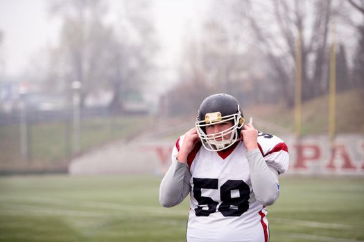 portrait of young confident American football player standing on the field during training