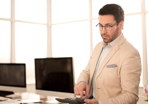 businessman holding a calculator while sitting at his Desk.business concept