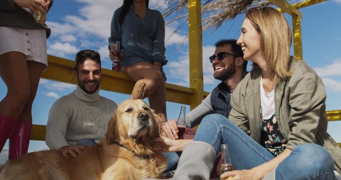 Happy Group Of Friends Hanging Out At Beach House having fun and drinking beer on autumn day