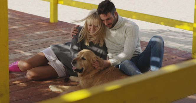 Couple With A Dog enjoying time  together On The Beach at autumn day