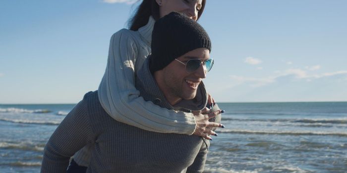 Men Giving Piggy Back Rides At Sunset By The Sea, autumn time