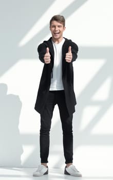 in full growth.smiling young man showing thumbs up.isolated on light background