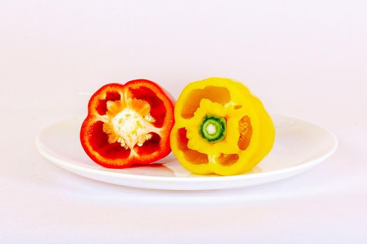 Bulgarian pepper red and sliced yellow lies on a white plate. The concept of a healthy diet.