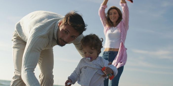 Family with kids resting and having fun at beach during autumn day