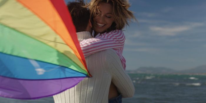 Loving Couple Flying A Kite at Beach and having fun on autumn day