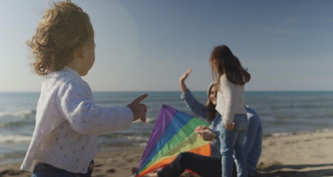 Family with kids resting and having fun at beach during autumn day