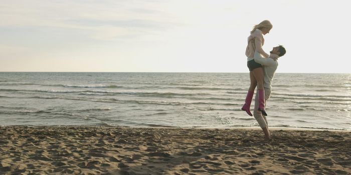 Young couple having fun on beach during autumn sunny day