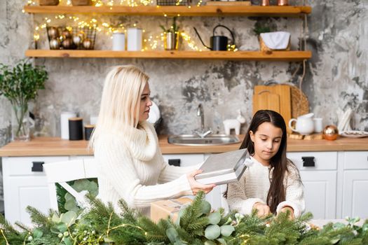 Beautiful young family enjoying their holiday time together, decorating Christmas tree, arranging the christmas lights and having fun.
