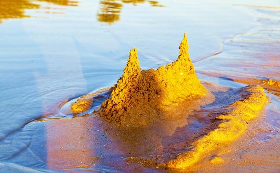 Beautiful sand castle illuminated by the morning sun on the beach of the tropical sea. The concept of a family vacation at sea.