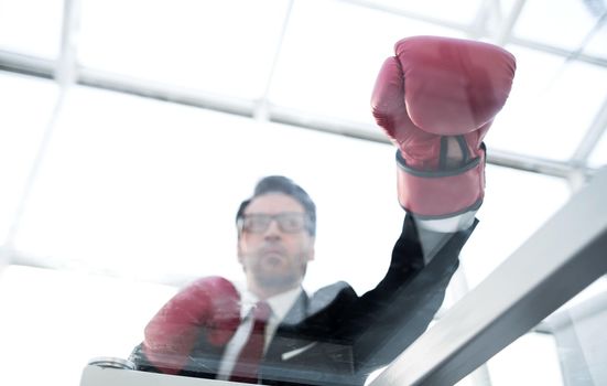 bottom view.businessman in Boxing gloves sitting at a glass table .business background