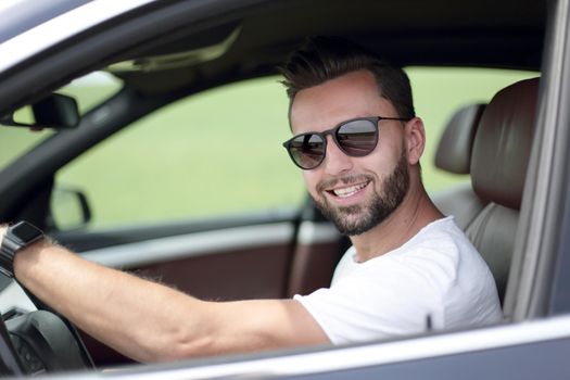 portrait of a stylish young man driving a convertible car