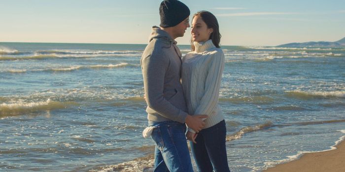 Cool Couple Laughing and hugging In Front Of Beach at beautiful autumn day