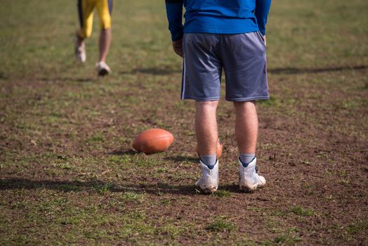 Team coach throwing the ball into the group of young american football players in action during the training at the field