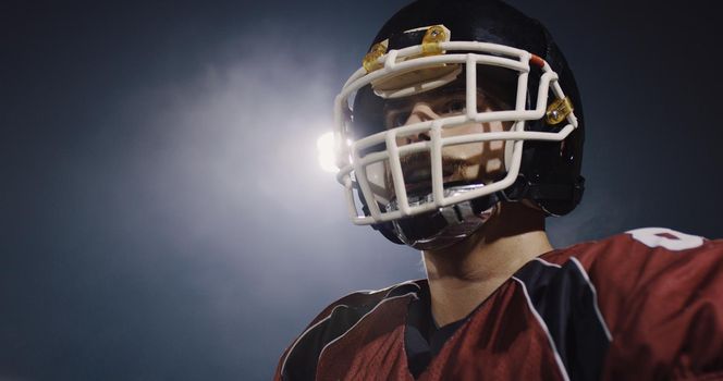 portrait of young confident American football player  standing on field at night