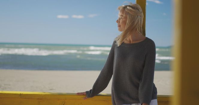 Young woman on the beach. The girl enjoying the warm autumn day. Portrait of beautiful girl near the water