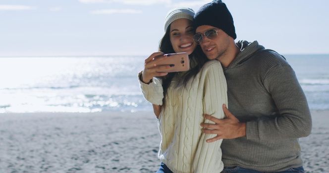 Very Happy Couple In Love Taking Selfie On The Beach in autmun day
