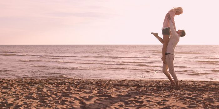 Young couple having fun on beach during autumn sunny day