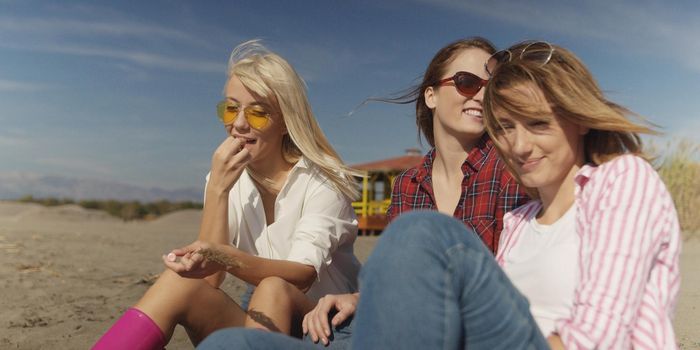Group Of Young girlfriends Spending The Day On A Beach during autumn day