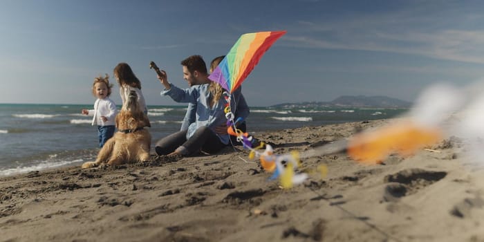 Family with kids resting and having fun at beach during autumn day