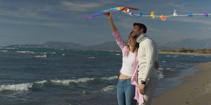 Loving Couple Flying A Kite at Beach and having fun on autumn day