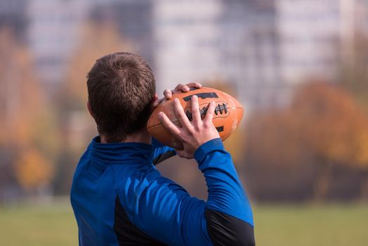 Team coach throwing the ball into the group of young american football players in action during the training at the field