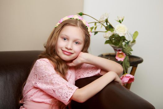 Happy little girl with a bouquet of flowers sitting on the couch. The concept of a holiday, a spring mood.