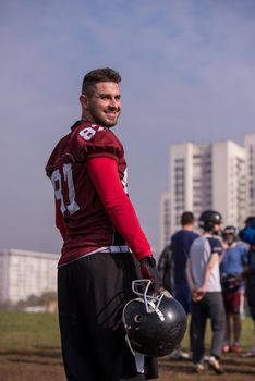 portrait of young confident American football player  standing on a field during the training